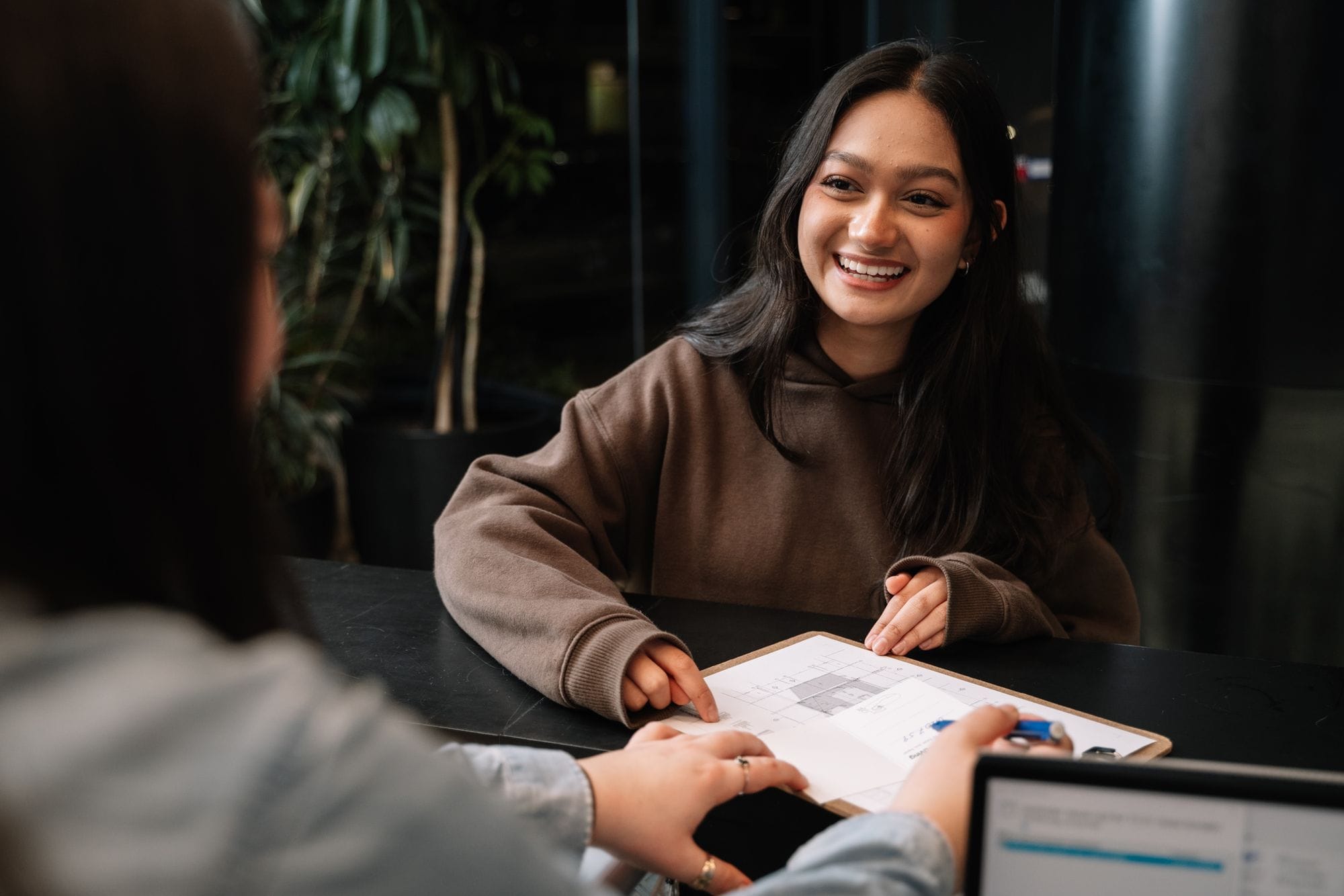 Two people discussing a document at a table in a modern office setting.