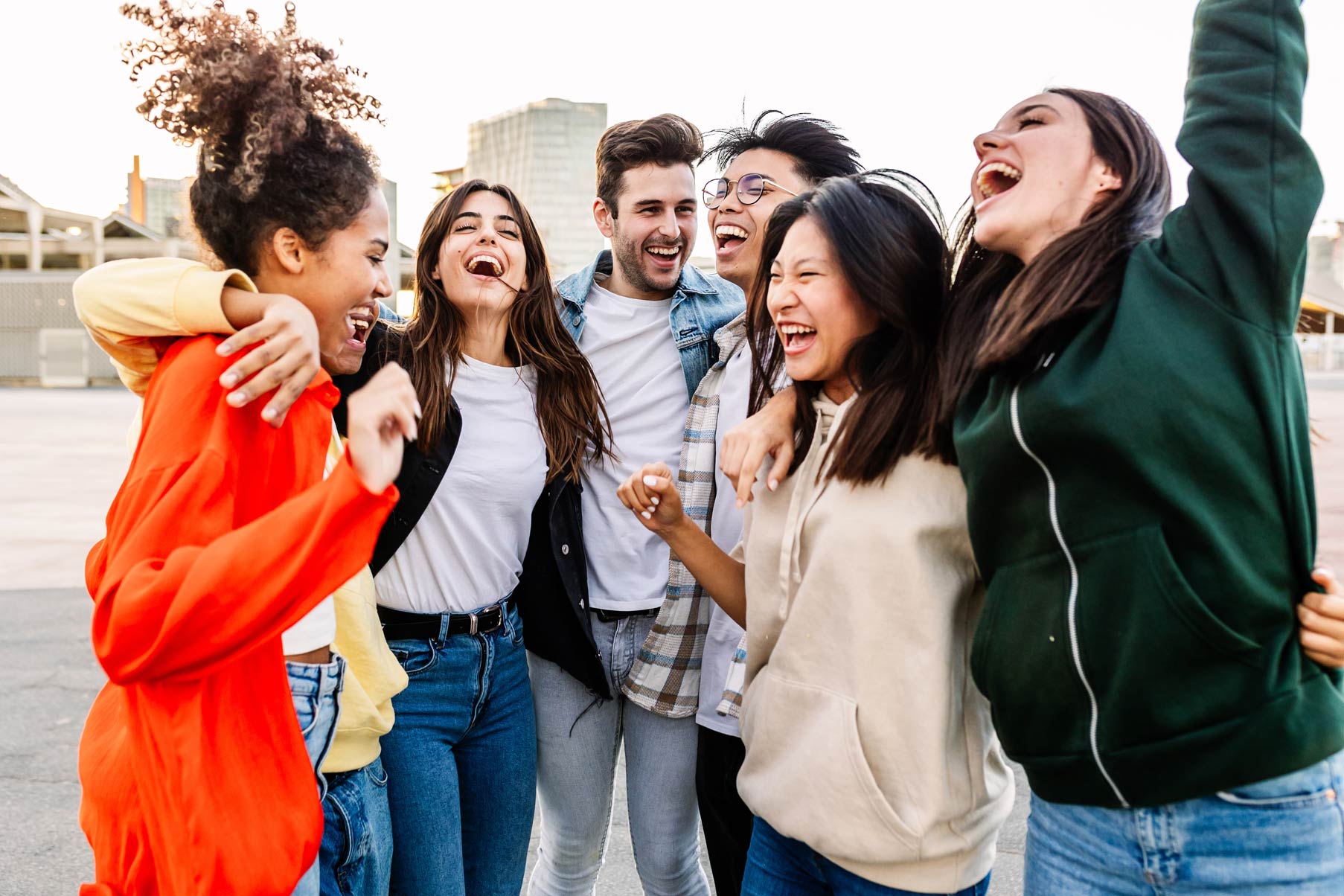 Group of friends smiling and hugging outdoors in a city setting.
