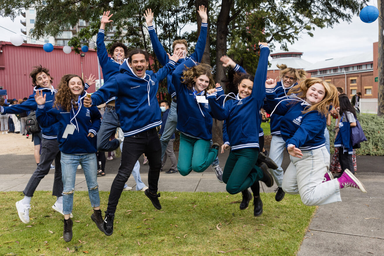 Group jumping outdoors in matching blue hoodies.