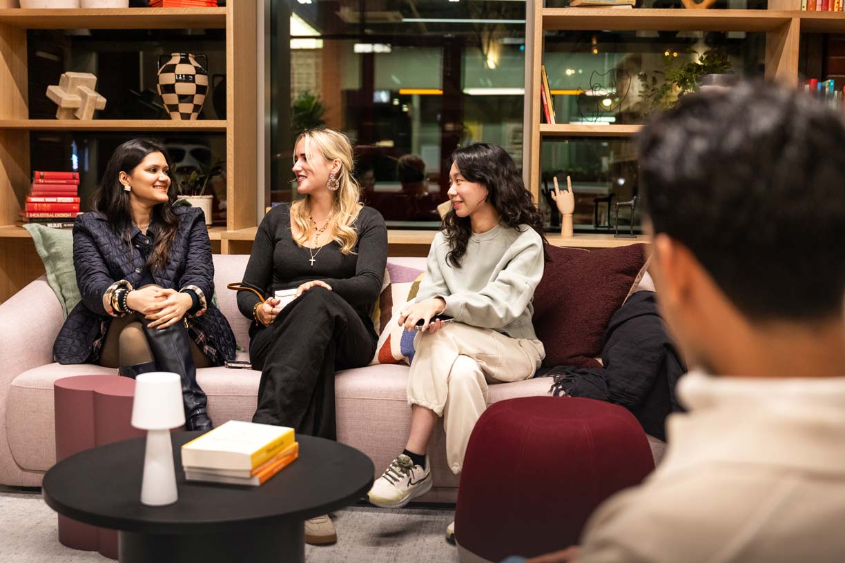 Two people working on laptops at a curved table in a bright, modern space.