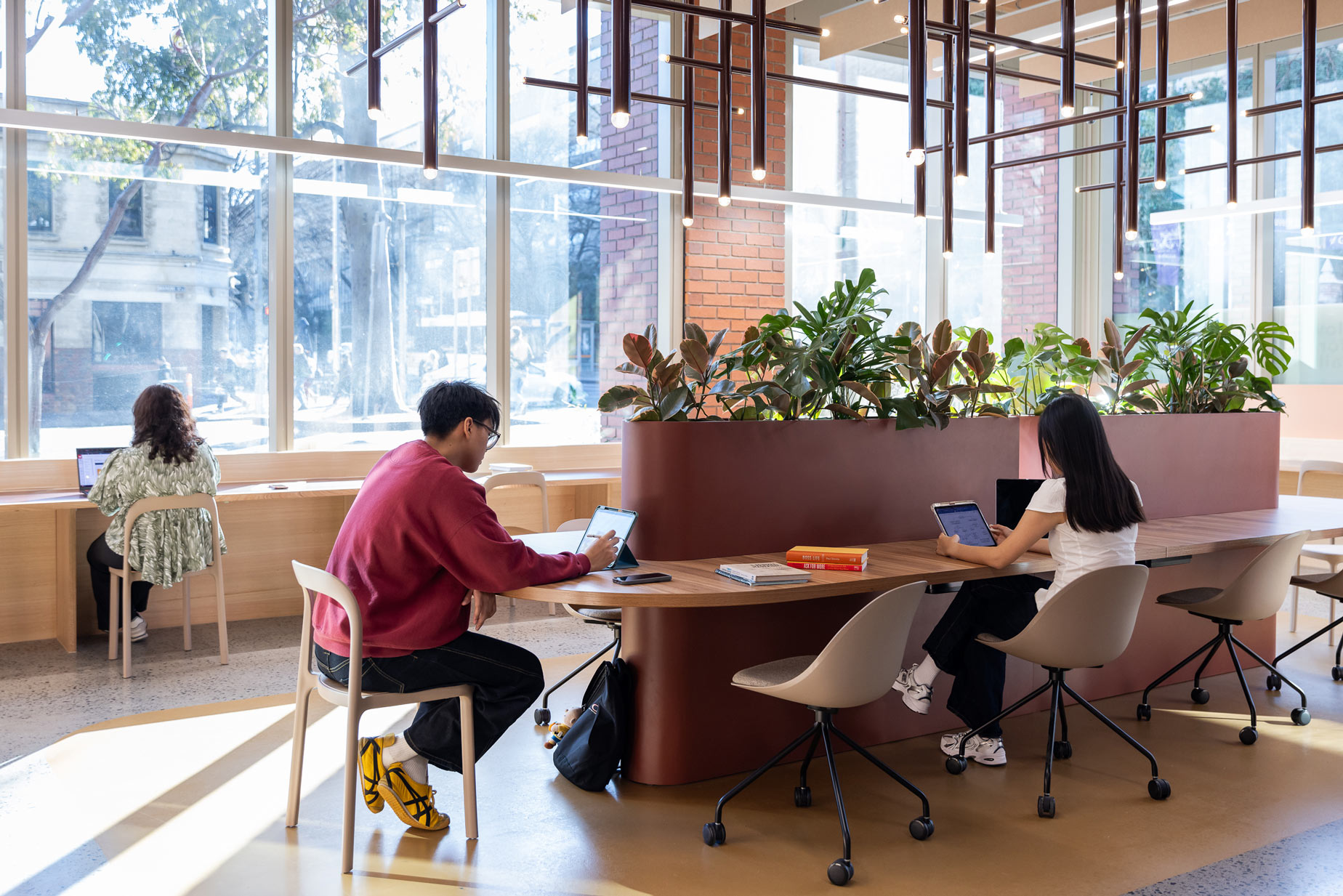 Two people working on laptops at a curved table in a bright, modern space.